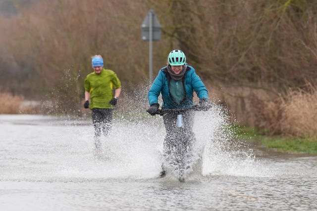 People cycle through flood water