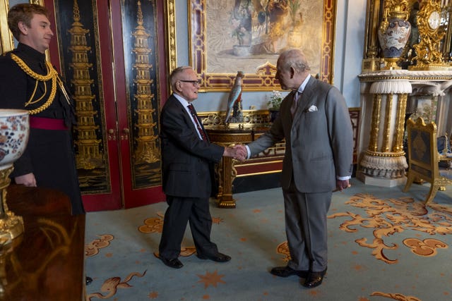 The King shakes hands with Flight Lieutenant Colin Bell as they meet during an audience in the Chinese Drawing Room at Buckingham Palace 
