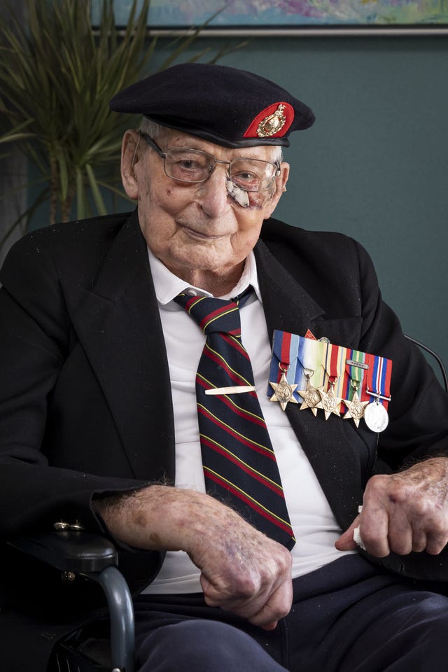 Elderly man in black jacket, striped tie and black beret. He wears a collection of medals on his chest
