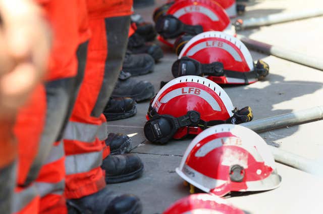 Firefighters lay their helmets on the ground during a minute's silence near to Grenfell Tower (Jonathan Brady/PA)