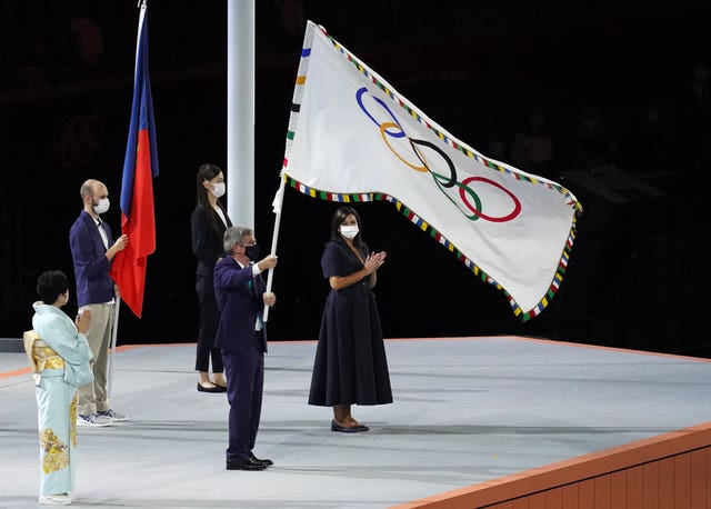 Thomas Bach holds the Olympic flag