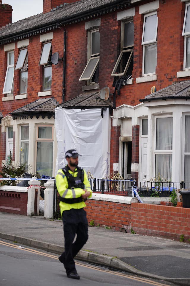 A police officer behind crime scene tape near a house in Blackpool