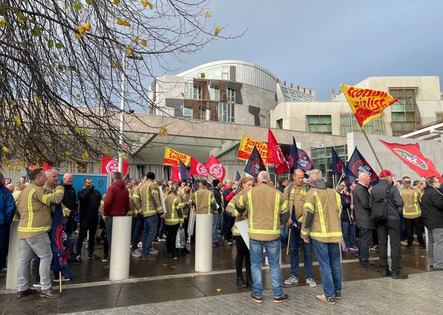 Flag waving protesters outside the Scottish Parliament, with the building in the background