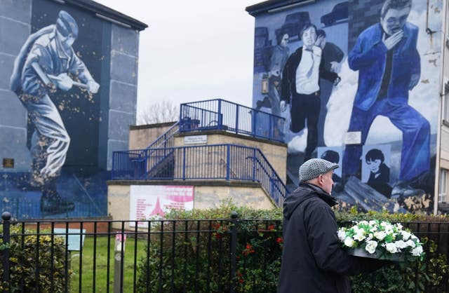 A man with flowers at the Bloody Sunday memorial in Derry