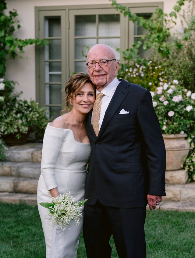 Rupert Murdoch wearing a suit and Elena Zhukova in a white dress in front of green doors