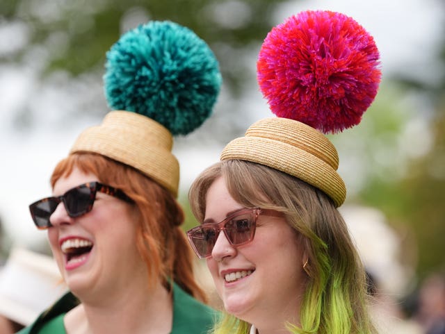 Two women wear hats with giant pom-poms
