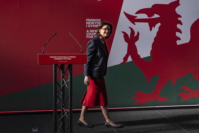 Baroness Morgan walks before a Welsh dragon image