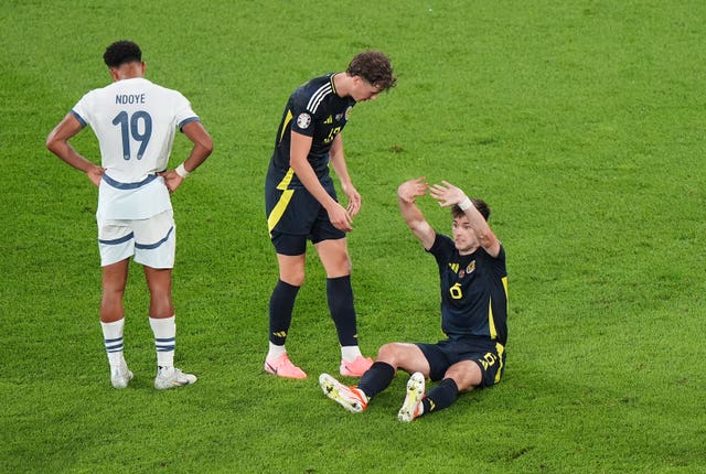 Scotland’s Kieran Tierney (right) signals he needs to be substituted as he sits on the pitch