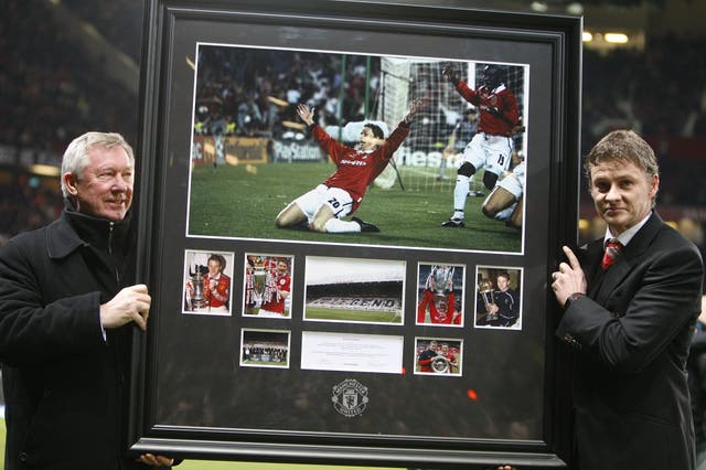 Manchester United manager Sir Alex Ferguson, left, presents Ole Gunnar Solskjaer with a framed selection of photographs from his Manchester United career, headlined by his celebration after scoring the winner in the Champions League final