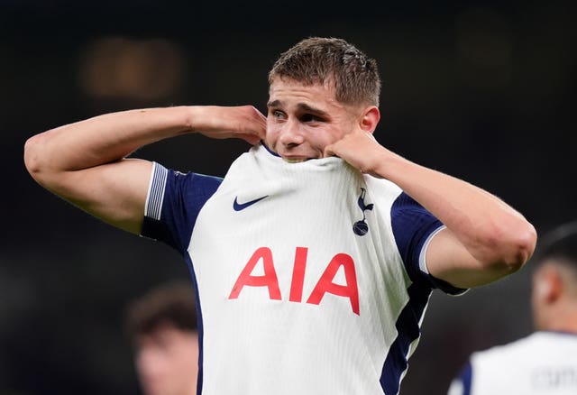 Micky van de Ven pulls his shirt above his mouth after suffering an injury