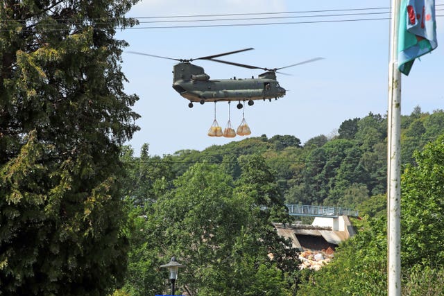 An RAF Chinook helicopter flies in sandbags to help repair the dam