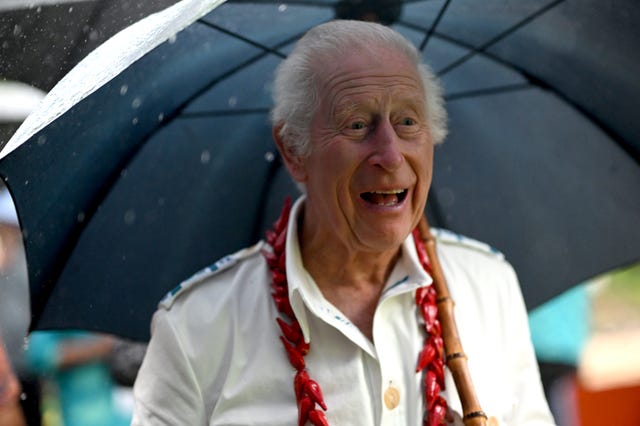 The King smiling and carrying an open umbrella during his tour to Samoa 