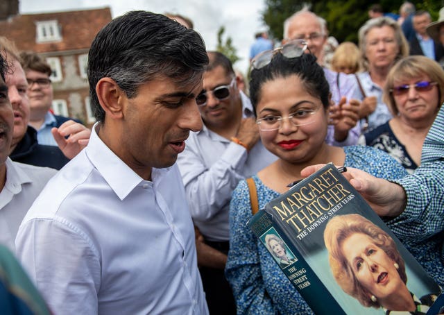 Rishi Sunak is handed a copy of former prime minister Margaret Thatcher’s book to sign at an event at Manor Farm, in Ropley near Winchester, Hampshire