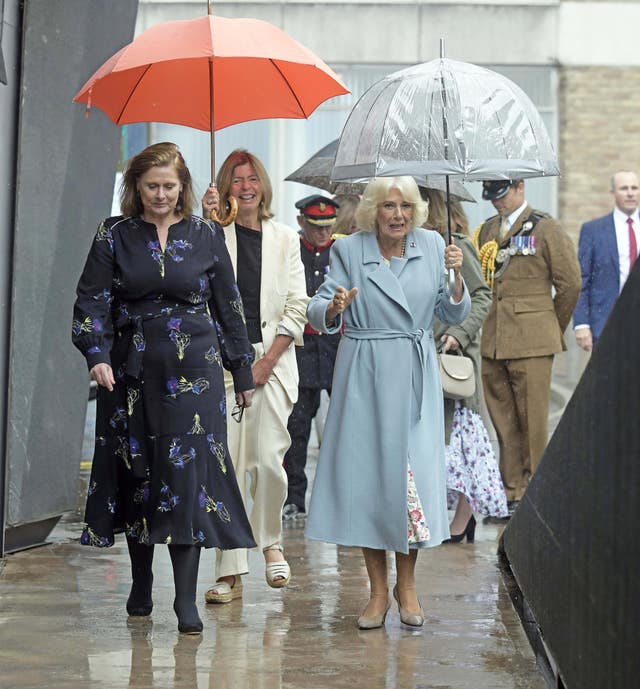 The Queen holds an umbrella while walking outside alongside Sarah Brown