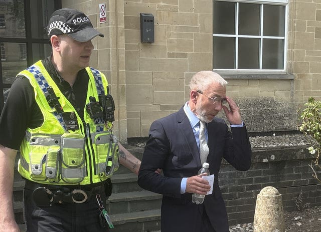 James Holder is escorted by a police officer as he leaves Cirencester Magistrates’ Court 