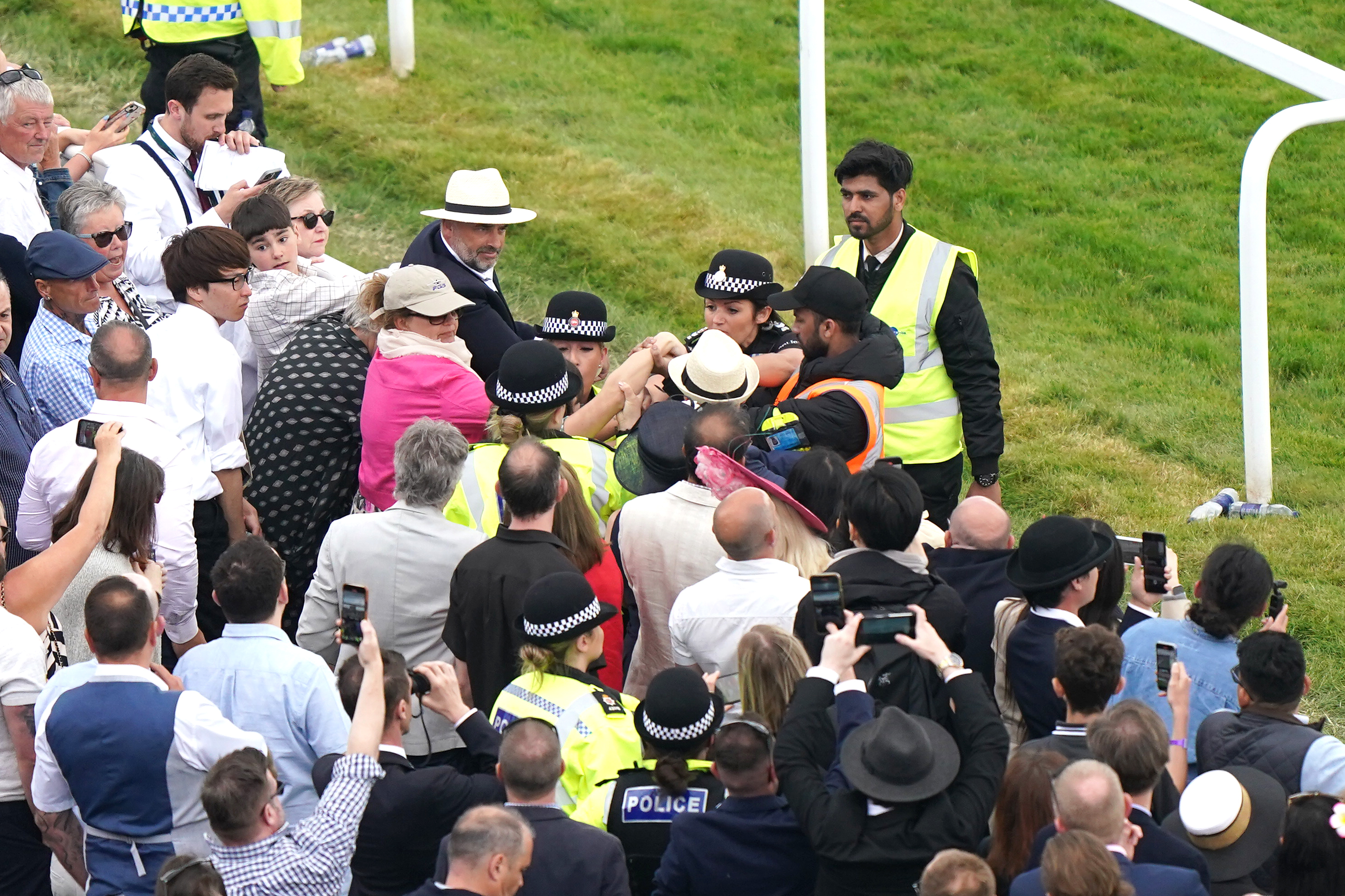 A spectator is detained by police in the crowd at Epsom