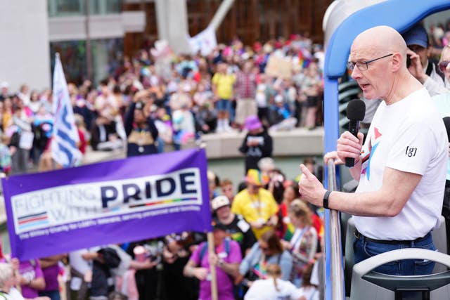 John Swinney wearing a Pride T-shirt addresses a crowd of people