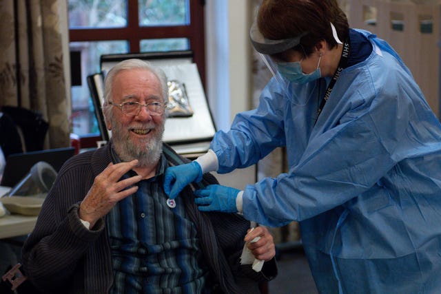 Care home resident Michael Starr is given a sticker by practice nurse Jenny Hughes, after getting his Oxford jab