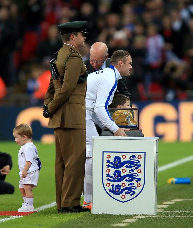 Wayne Rooney, centre, receives a golden cap from Sir Bobby Charlton, back, in 2014 to mark his 100th England appearance