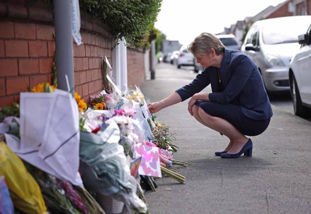 Home Secretary Yvette Cooper reads messages left on flowers