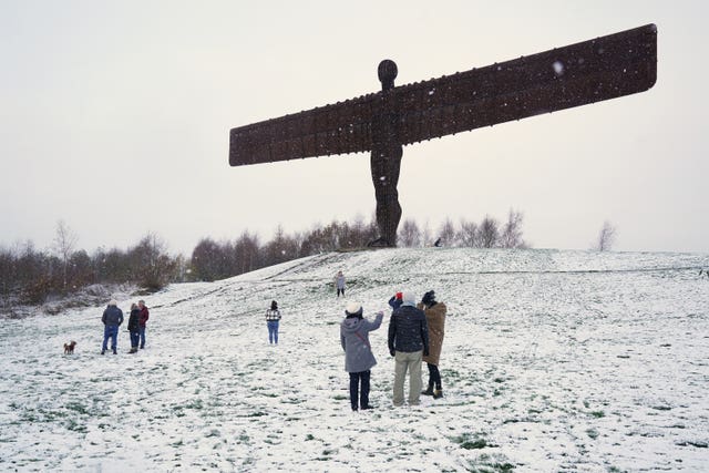 People at a snow-covered Angel of the North in Gateshead