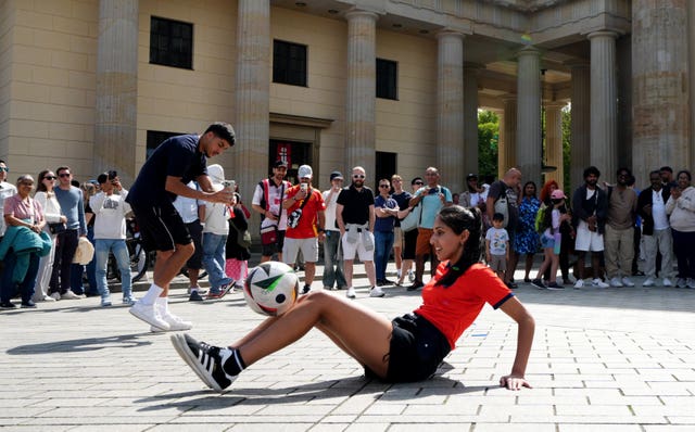 An England fan plays with a football next to the Brandenburg Gate 