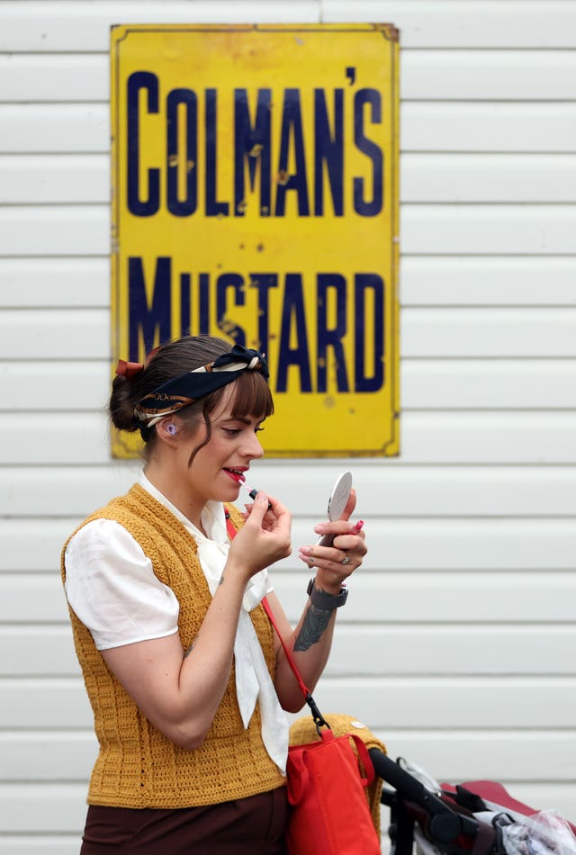 A woman applies make-up in front of a Colman's Mustard sign