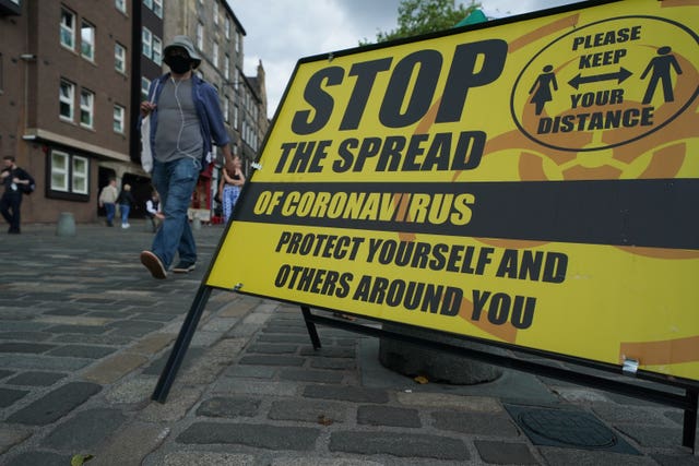 A yellow Covid-19 information sign on a street in Edinburgh