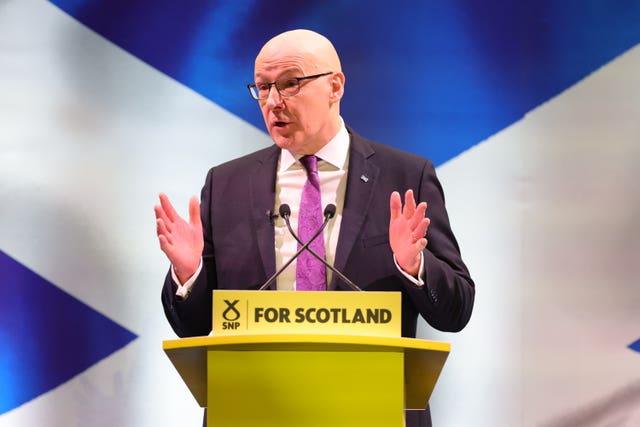 John Swinney speaking from an SNP lectern