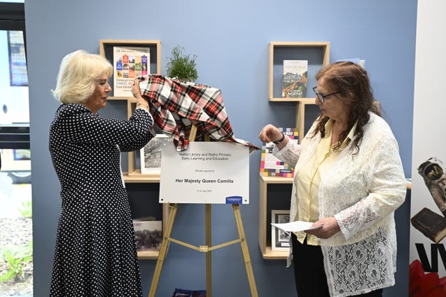 King lifts a tartan cloth to reveal a plaque marking her visit