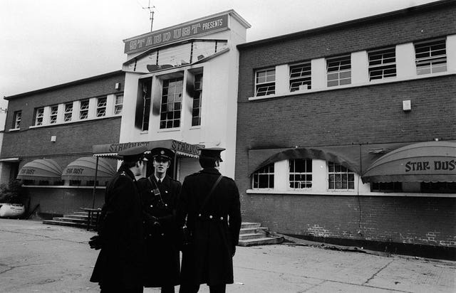 Police stand outside the main entrance of a fire-blackened Stardust Disco in Artane, Dublin, in 1981 