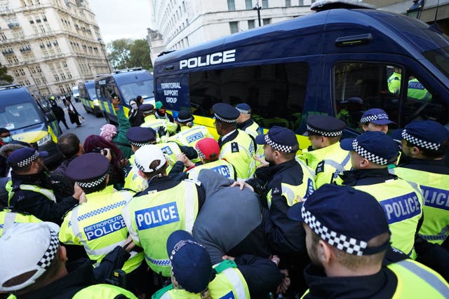 Police officers escort a protester who was arrested close to Downing Street during a March for Palestine in London. 