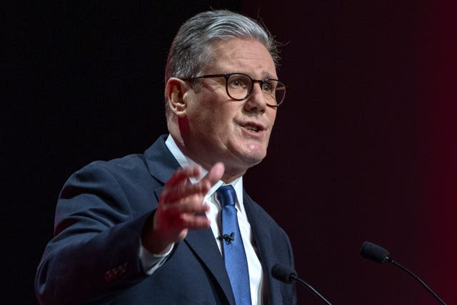 Sir Keir Starmer gesturing with one hand while speaking into microphones