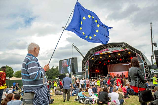 A man carrying an EU flag watches a performance by Glen Matlock from the Sex Pistols