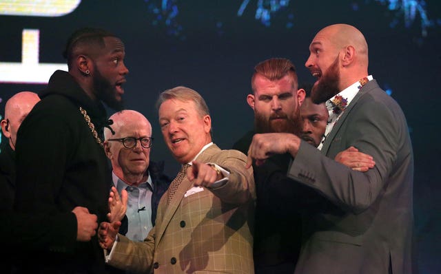 Deontay Wilder (left) and Tyson Fury (right) react as promoter Frank Warren (centre) keeps them apart during a press conference