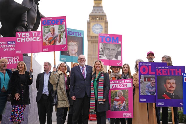 Terminally ill people and bereaved family members holding placards alongside Kim Leadbeater in Parliament Square with the Elizabeth Tower in the background
