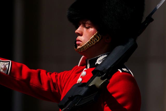 A member of F Company Scots Guards swelters in the heat during the Changing of the Guard ceremony on the forecourt of Buckingham Palace, central London