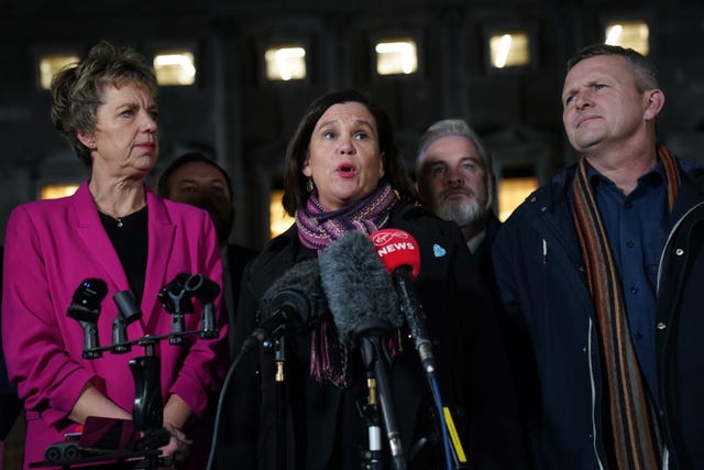 Mary Lou McDonald speaking into microphones, flanked by other politicians