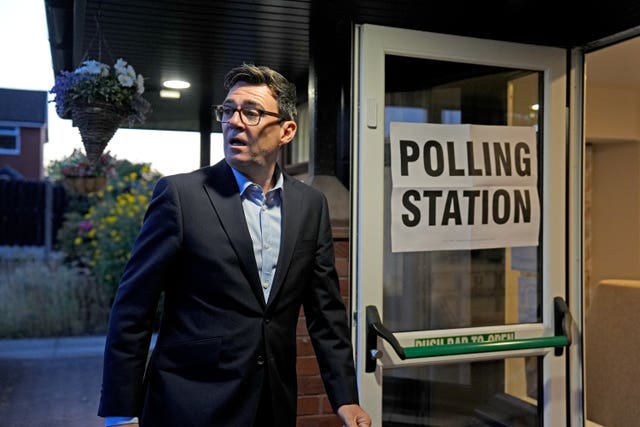Andy Burnham walks through a door marked 'Polling Station'