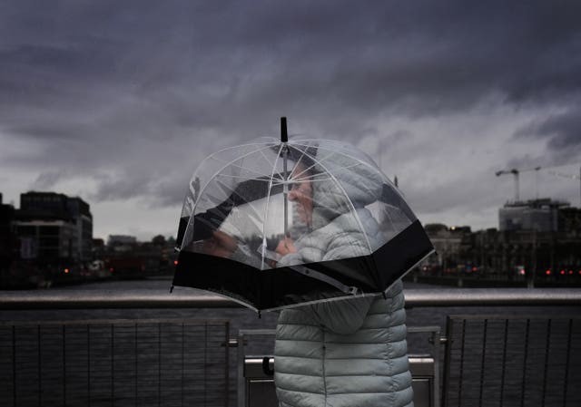 Woman under umbrella amid dark skies