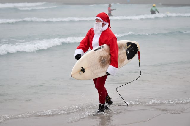 A surfer gets into the festive spirit dressed as Santa as he prepares to enter the waves at the inland surfing lagoon at The Wave, near Bristol