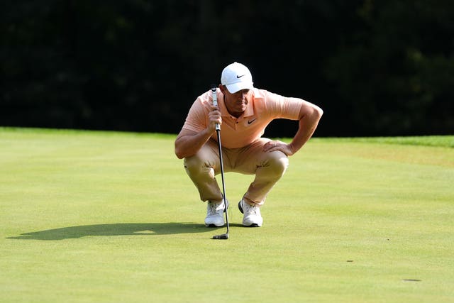 Rory McIlroy crouches down to read a putt on the green