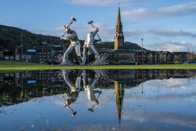 The Shipbuilders of Port Glasgow sculpture in Coronation Park, Inverclyde, is reflected in large puddles after heavy downpours