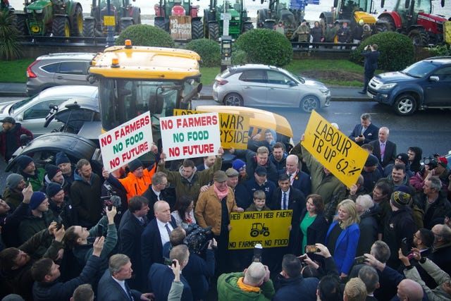 Farmers holding signs stand in front of a tractor with Rishi Sunak 