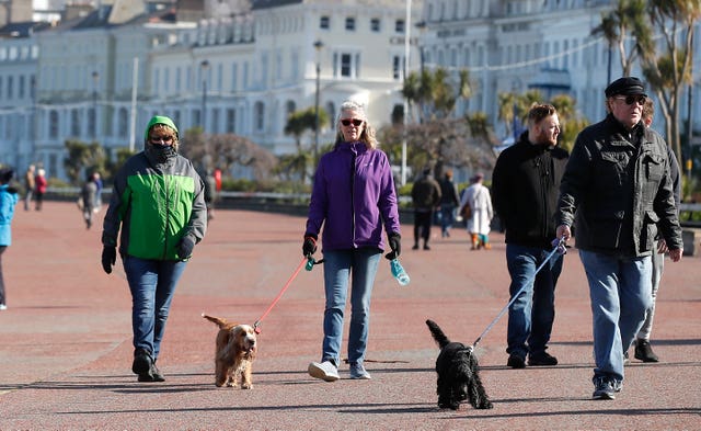 People walk along the promenade in Llandudno, north Wales, as the Government continues to advise the public to reduce social interaction