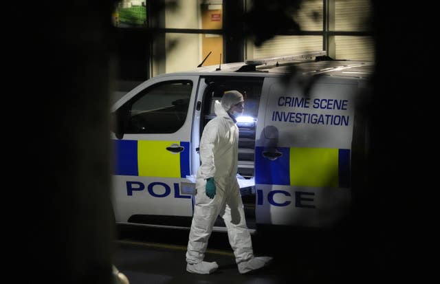 A forensic officer dressed in white walks away from a police van