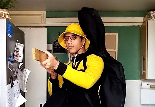 Nicholas Prosper holding a plank of wood as a mock gun