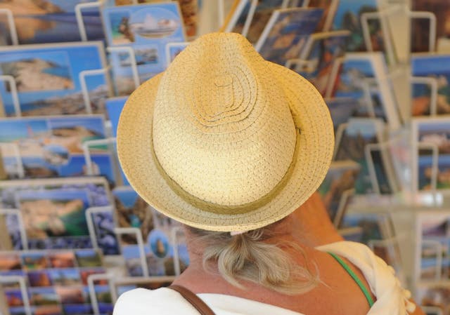 A woman looking at holiday postcards in Praia da Luz, Portugal