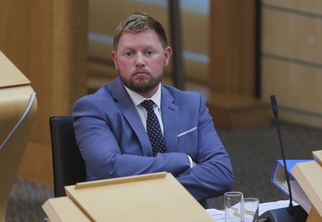 Jamie Greene with arms folded while seated in Parliament