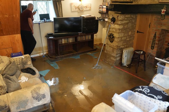 A man looking out of the window of his flooded house in Grendon, Northamptonshire